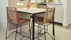 Una cocina moderna con armarios blancos, un espejo redondo y una mesa de comedor con sillas de mimbre.