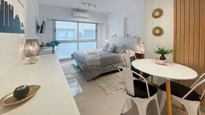 Un dormitorio moderno con cama, mesita de noche y una pequeña mesa redonda con sillas.