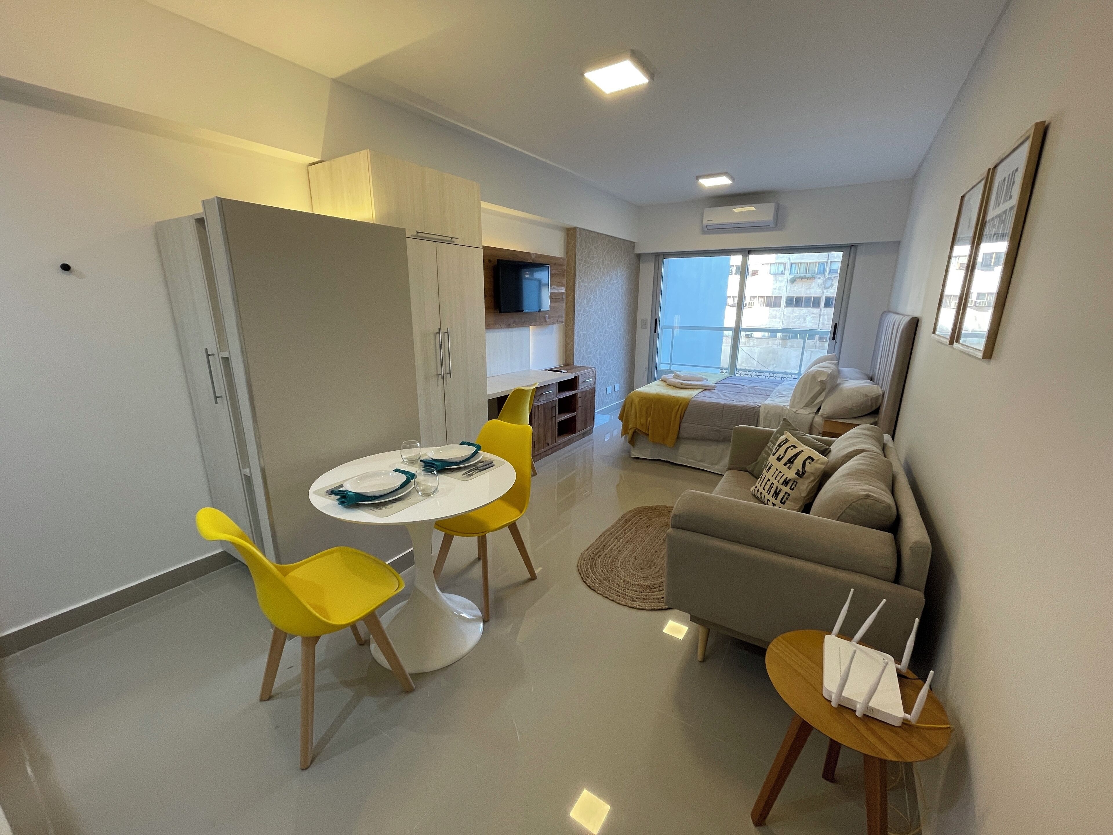 Eine moderne Wohnung mit Essbereich, einer Couch, einem Fernseher und einem Balkon mit Blick.