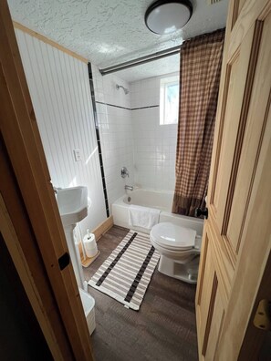 A bathroom with a bathtub, toilet, and sink.