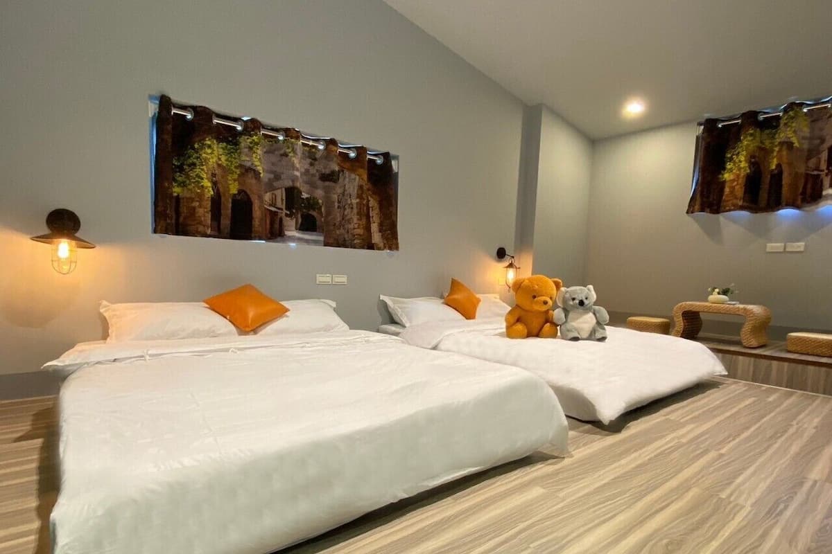 Une chambre d’hôtel avec deux lits, un ours en peluche et un tableau accroché au mur.