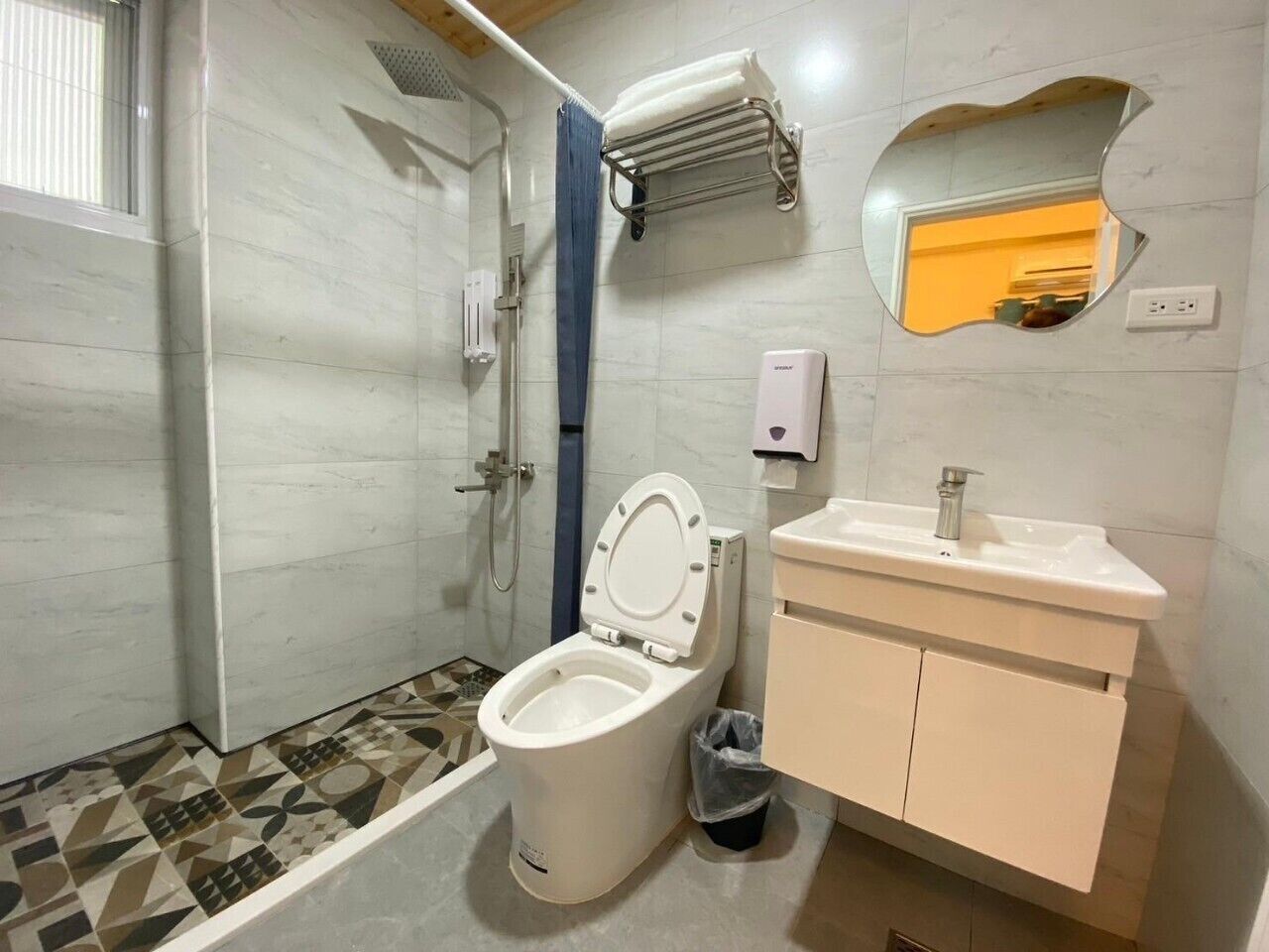 A bathroom with a toilet, sink, mirror, and shower.