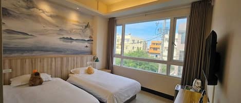 A hotel room with two beds, a large window with a city view, a painting on the wall, and a wooden desk with a mirror.