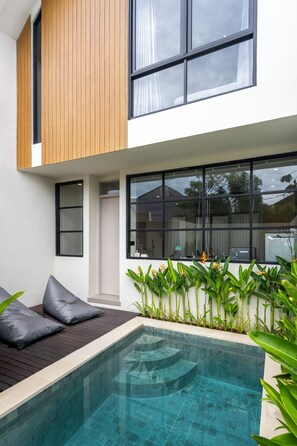 A modern house with a swimming pool, wooden deck, and large windows. - Jane Berawa Villa by Betterplace (Canggu)
