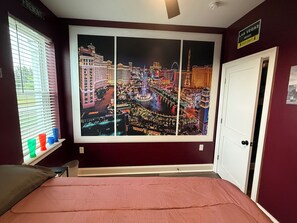 Quarto de hotel com vista ampla para a cidade, uma cama, uma janela com persianas e uma porta.