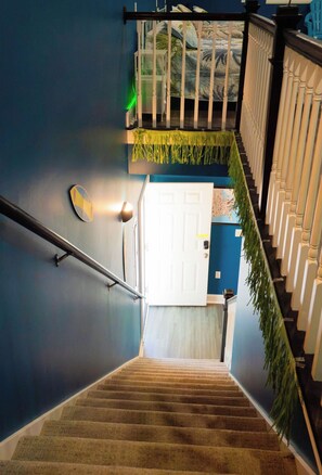Uma escadaria com corrimão, uma porta branca na base e uma parede azul.
