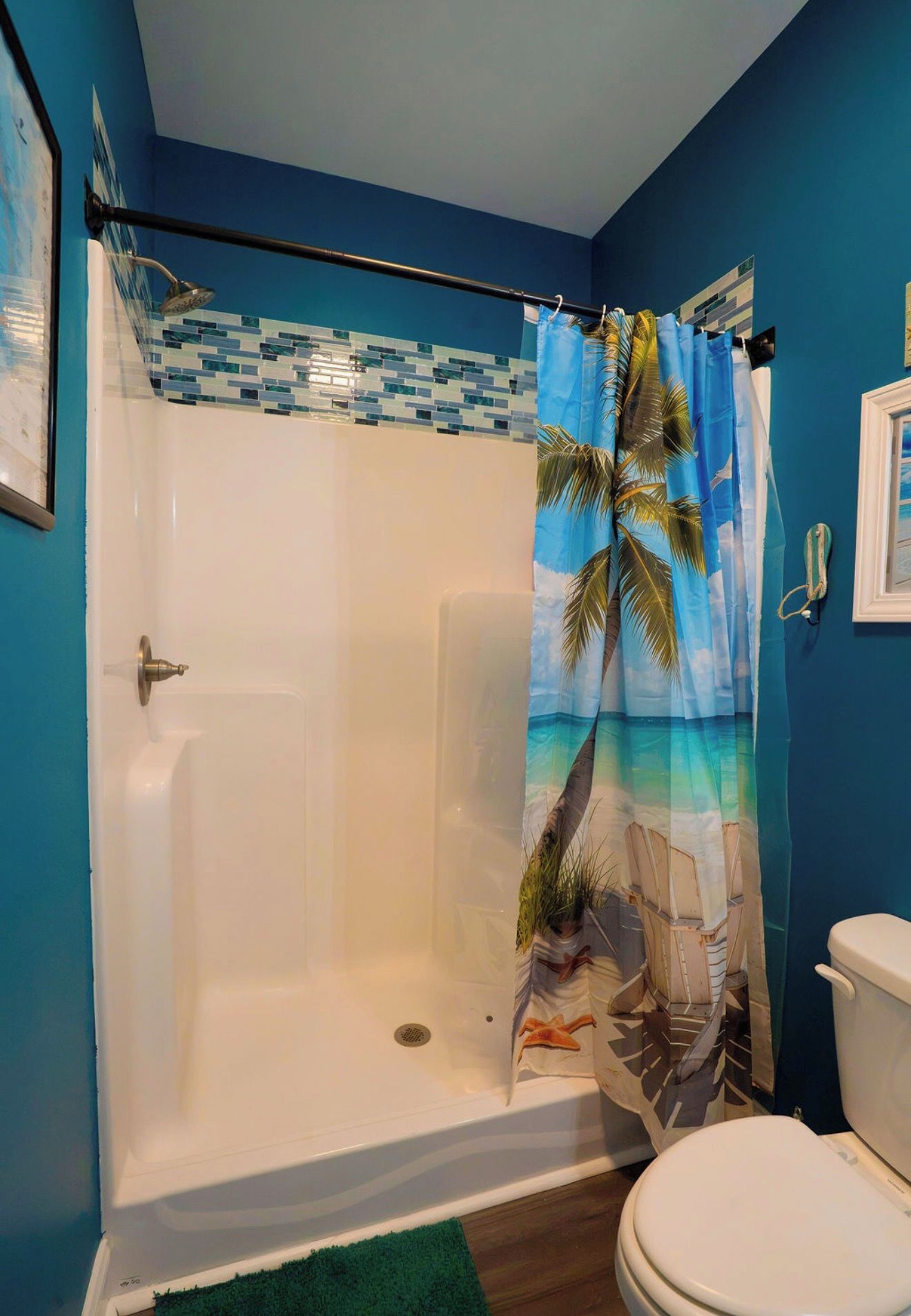 A bathroom with a shower, toilet, and a blue wall.