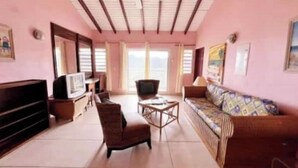 Una sala de estar con sofá, sillón, televisor y ventilador de techo.