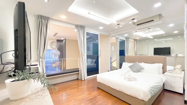 A modern hotel room with a large bed, a TV, a potted plant, and a view of the city through the window. - The Scott Garden by Manhattan Group  (Kuala Lumpur)