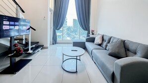 A modern living room with a grey sofa, a coffee table, and a TV displaying entertainment options. - The Scott Garden by Manhattan Group  (Kuala Lumpur)