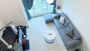 A modern living room with a grey sofa, a round coffee table, and a staircase leading to an upper floor. - The Scott Garden by Manhattan Group  (Kuala Lumpur)