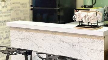 A kitchen counter with a marble backsplash, a coffee maker, and a towel rack.