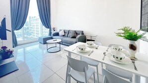 A modern living room with a sofa, a dining table set for two, and a large window with curtains. - The Scott Garden by Manhattan Group  (Kuala Lumpur)