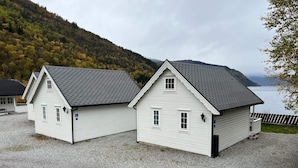 Two white buildings with grey roofs, a gravel driveway, and a lake view. - Holiday Home in Kinsarvik With Lake View (Ullensvang)