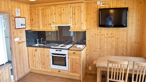 A wooden-paneled kitchen with a stove, oven, and a TV mounted on the wall. - Holiday Home in Kinsarvik With Lake View (Ullensvang)