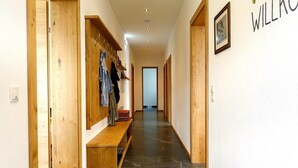 Un couloir avec des étagères en bois où sont exposés des vêtements, un banc et une enseigne « WILLKC » accrochée au mur.