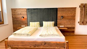 Un lit double avec un cadre et une tête de lit en bois, deux oreillers et une table de chevet avec une lampe.