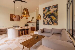 A modern living space with a kitchen island, a sofa, and pendant lighting.
