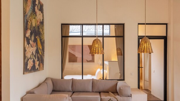 A living room with a beige sofa, a wooden coffee table, and two hanging wicker lamps. - Sofia Villa by Betterplace (Canggu)