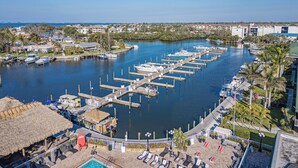 A marina with docks and boats, a pool area with sun loungers, and a thatched-roof structure. - Condo at the Bay with Resort-Style Amenities, Pool, Tiki Bar (Sarasota)