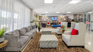 A modern hotel lobby with a grey sofa, a grey armchair, and a patterned carpet. - Condo at the Bay with Resort-Style Amenities, Pool, Tiki Bar (Sarasota)