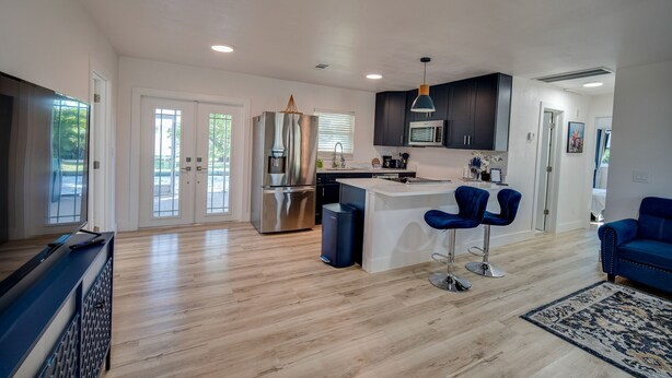 A modern kitchen with a central island, dark cabinetry, and a stainless steel refrigerator.