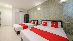 Ein Hotelzimmer mit zwei Betten, jeweils mit weißer Bettwäsche und roten Akzenten, einem Kleiderschrank und einer Wand mit Muster.