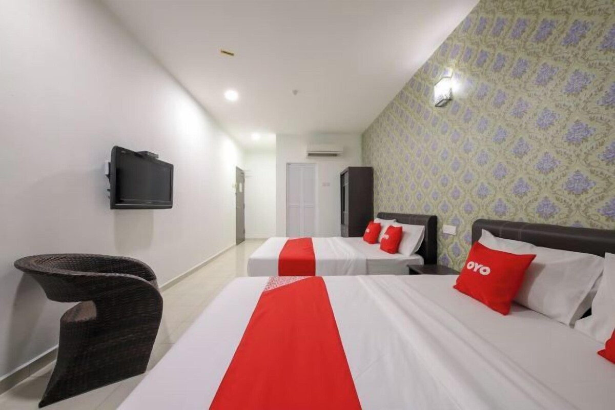 A hotel room with two beds, a television mounted on the wall, and a patterned wallpaper.