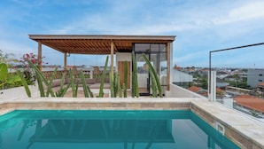 A rooftop pool area with a wooden pergola, cacti, and a view of the cityscape. - Leo Villa by Betterplace (Canggu)