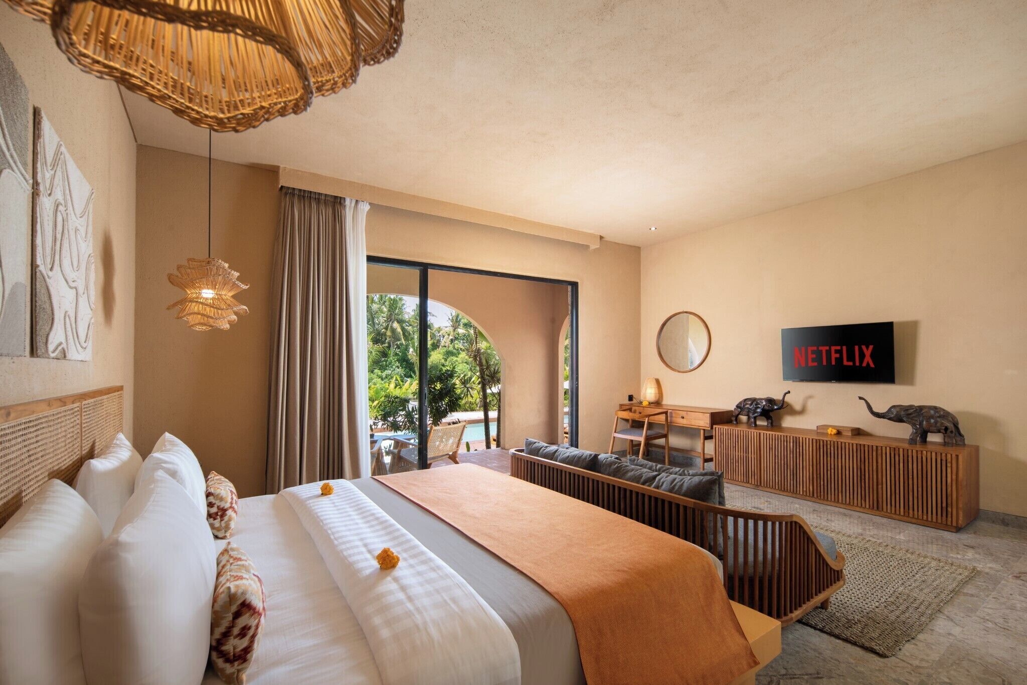 A modern hotel room with a large bed, a desk, a TV, and a view of the outdoors.