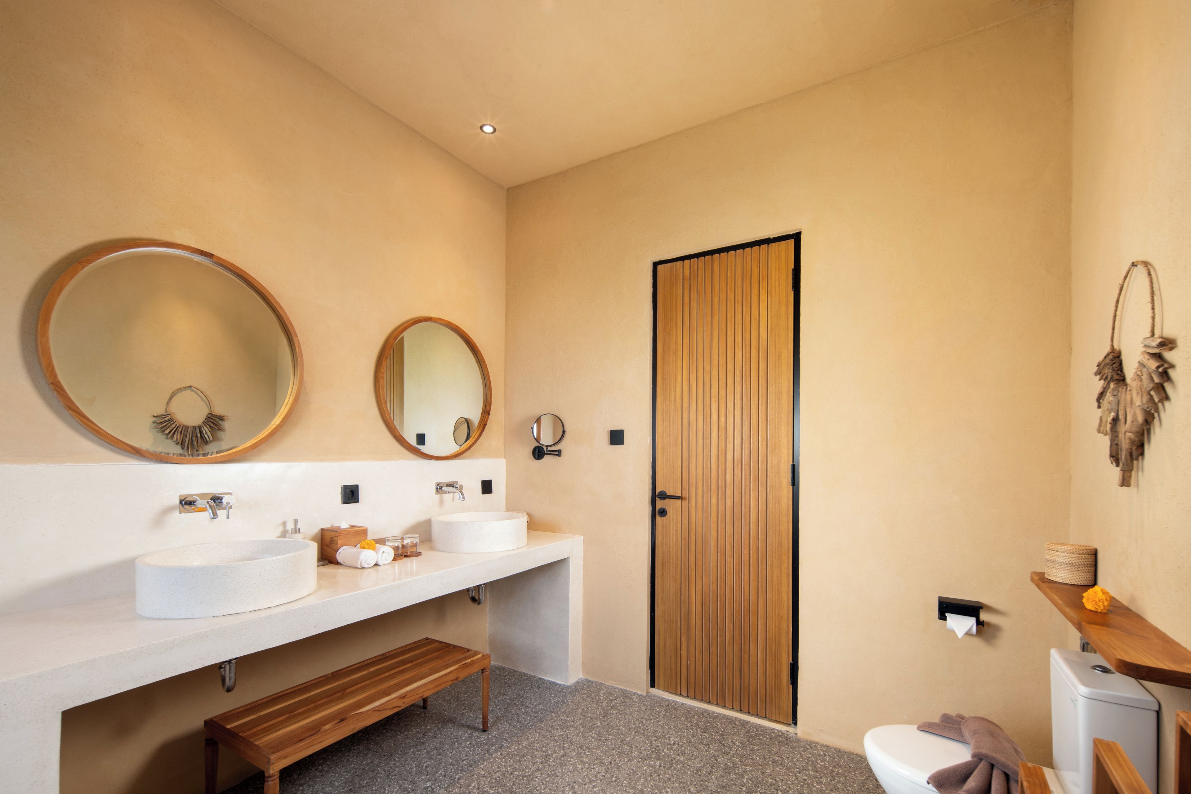Une salle de bain moderne avec un lavabo rond, un banc en bois et des toilettes.