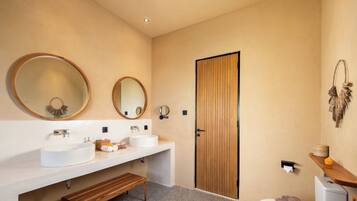 Une salle de bain moderne avec un lavabo rond, un banc en bois et des toilettes.