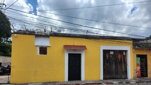 Un edificio amarillo con puerta negra y toldo rojo.