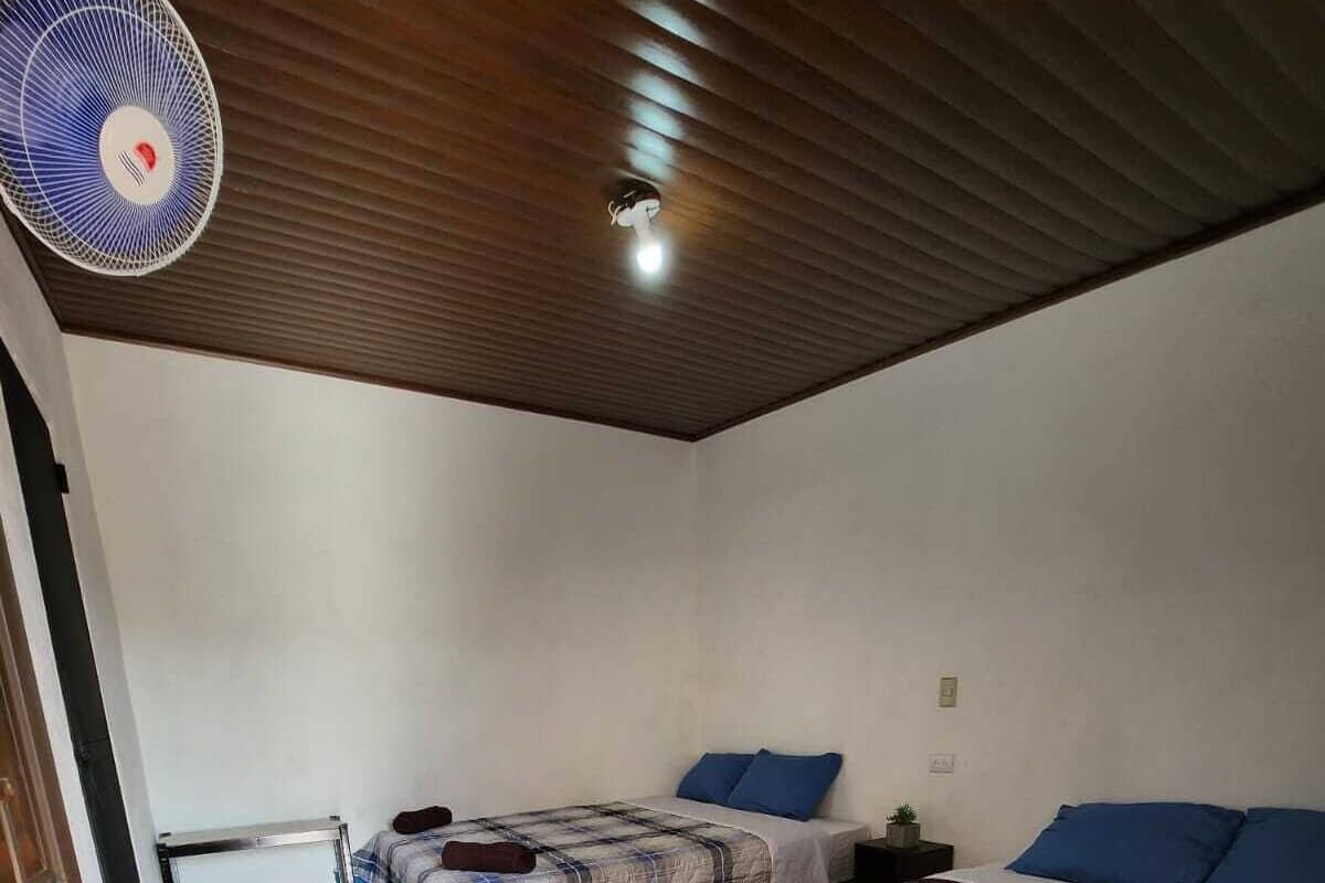 A room with two beds, a ceiling fan, and a tiled floor.