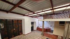 Un espacio interior amplio con piso de piedra, puerta de madera y estructura de techo metálica.