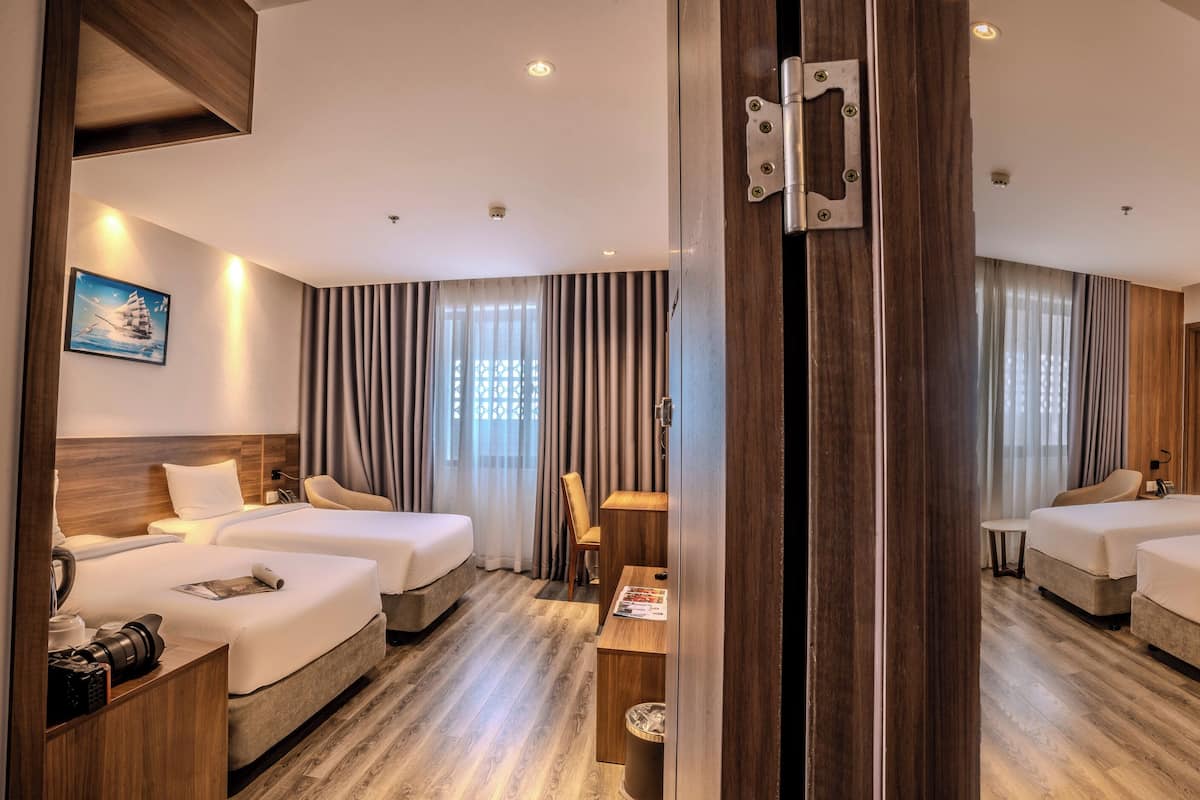 Ein Hotelzimmer mit Spiegel, zwei Betten, einem Schreibtisch, einem Stuhl und einem kleinen Tisch.