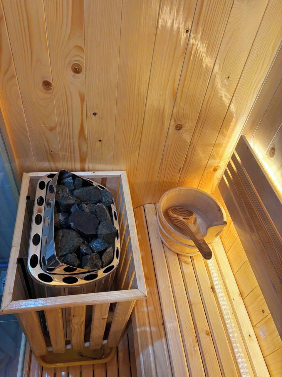 A sauna with wooden walls, a stone basin, and a wooden ladle.