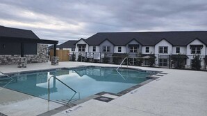 A swimming pool with a metal ladder, surrounded by a paved area with stone pillars. - Serenity I, Luxurious get-away, Pool, WIFI (Princeton)