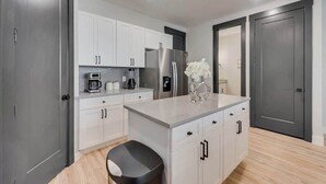 A modern kitchen with white cabinets, a stainless steel refrigerator, a coffee maker, and a vase with flowers on the counter. - Serenity I, Luxurious get-away, Pool, WIFI (Princeton)