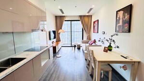 Una cocina moderna con estufa integrada, un comedor con mesa y sillas, y un amplio ventanal con cortinas.