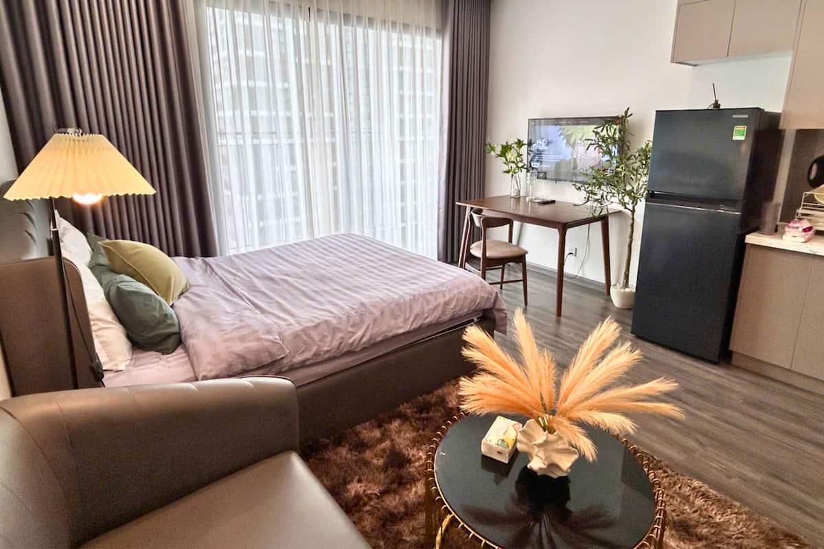 Moderni hotellihuone, jossa on sänky, sohva, ruokapöytä ja pieni keittiö.