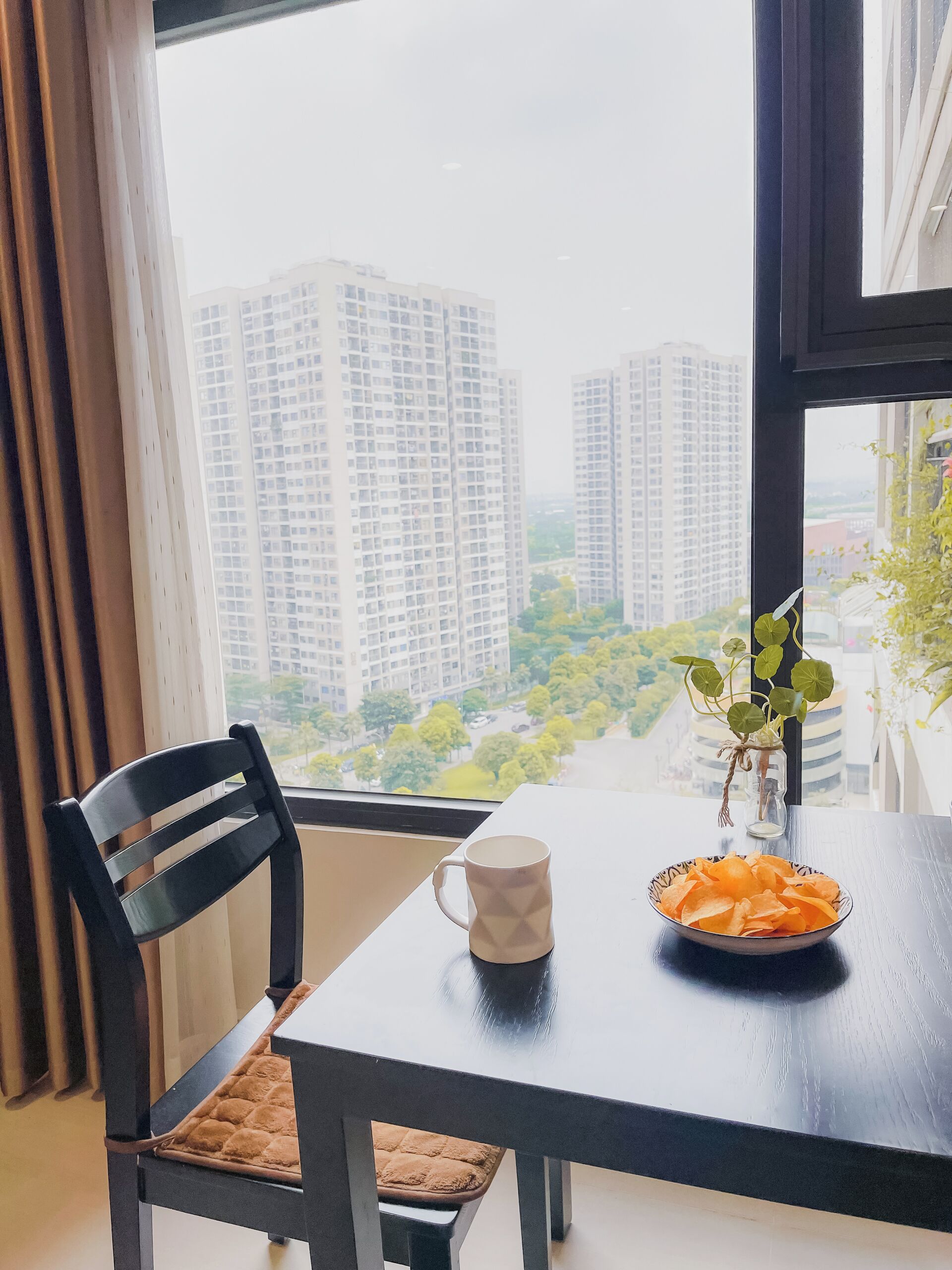 A dining area with a table, a chair, a mug, and a bowl of snacks.