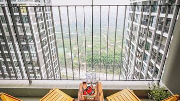 Enjoy the city view from this balcony with a table and two chairs, perfect for a refreshing drink.