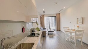 Una cocina moderna con una isla grande, un comedor con mesa y sillas blancas, y vistas de la ciudad a través de amplios ventanales.
