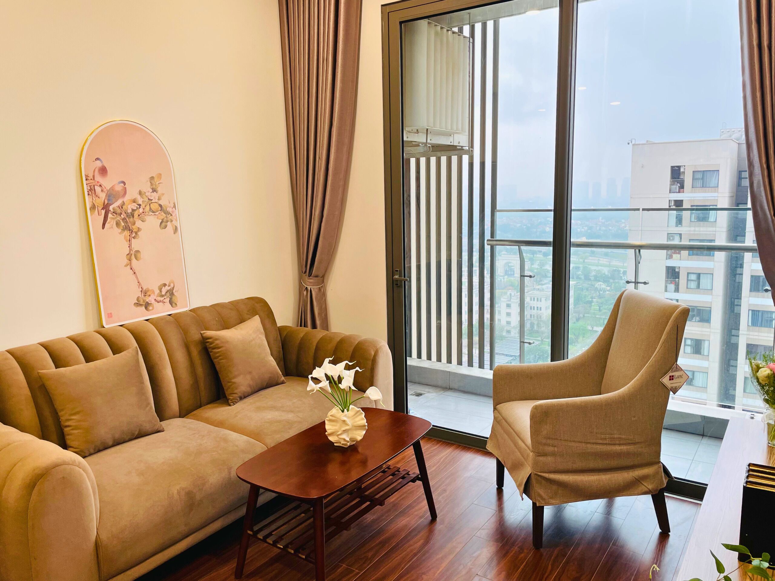 A modern living room with a sofa, armchair, and a coffee table with a vase of flowers.