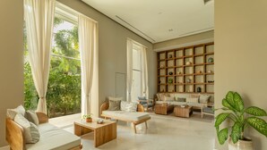 A spacious living room with a sofa, coffee table, and a bookshelf filled with decorative items.