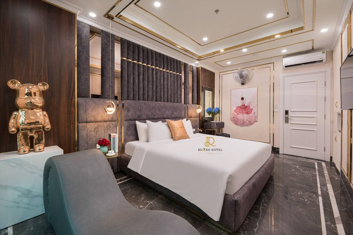 A modern hotel room with a large bed, a seating area, and a decorative bear statue.