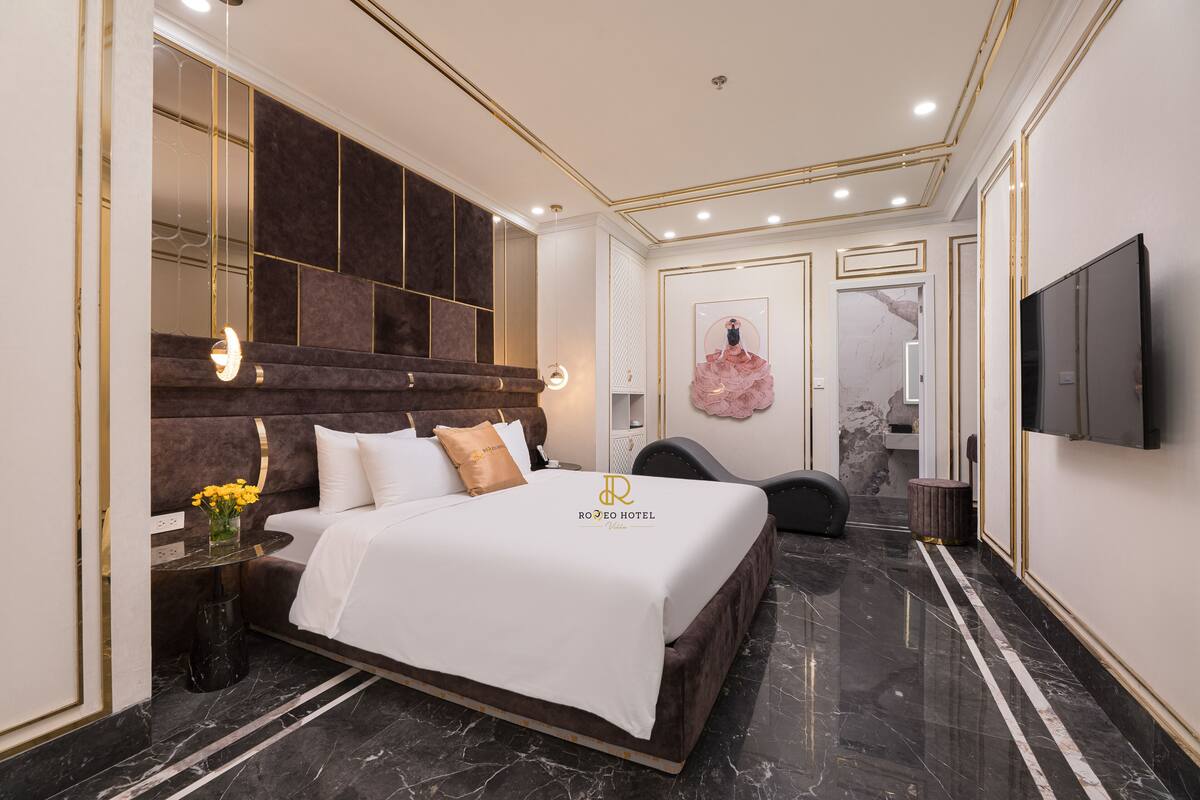 A modern hotel room with a large bed, a flat-screen TV, and a marble floor.