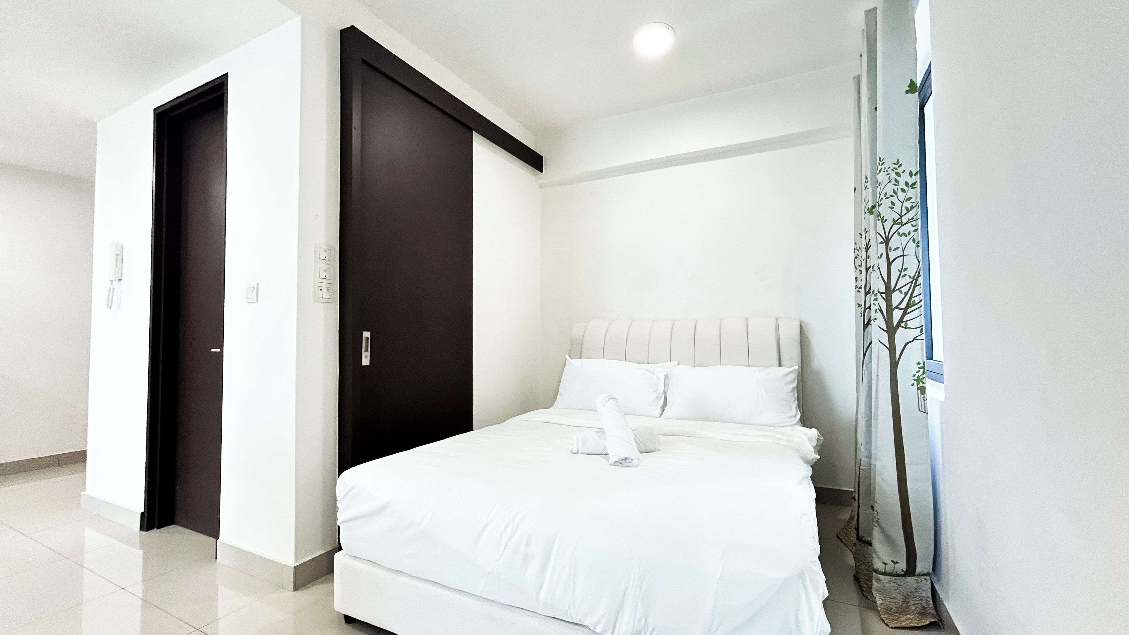 Une chambre d’hôtel avec un lit, une porte sombre et un mur blanc.