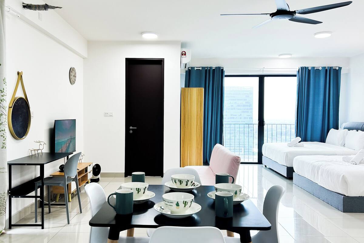 Ein modernes Hotelzimmer mit Balkon, einer Essecke mit Tisch für zwei Personen und einem Bett mit weißer Bettwäsche.